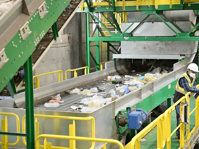Photo of rubbish being transported on a conveyor belt in a waste management facility