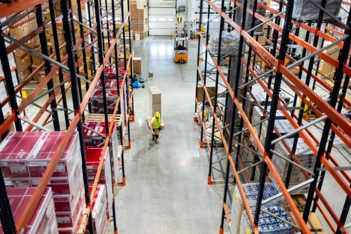 a warehouse with high shelving and a worker moving stock