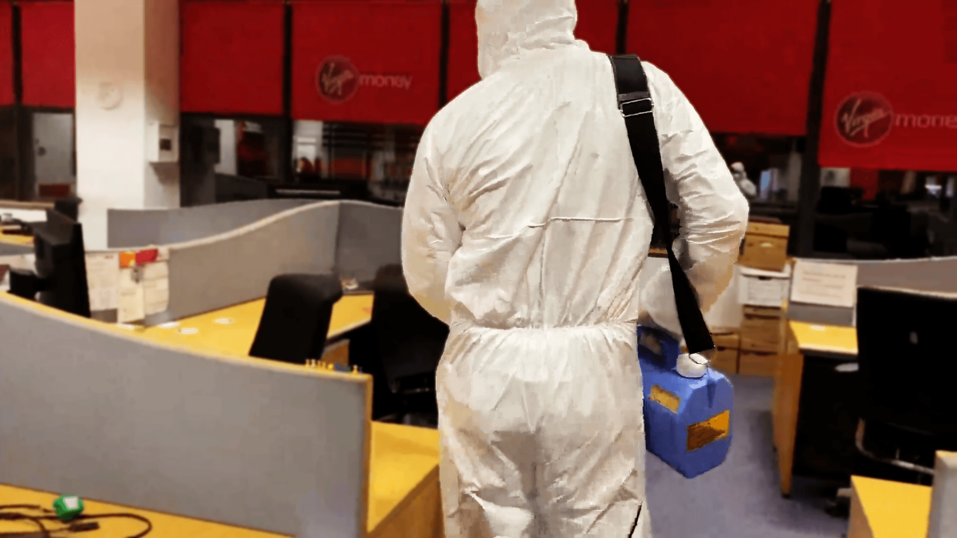 A employee wearing protective gear disinfecting an office area