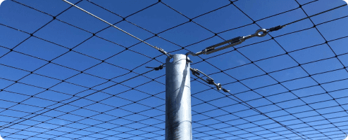 Close up of bird netting against a blue sky