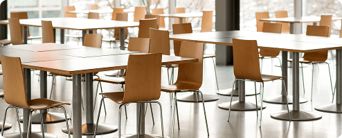 Several tables and chairs in a canteen with glass windows